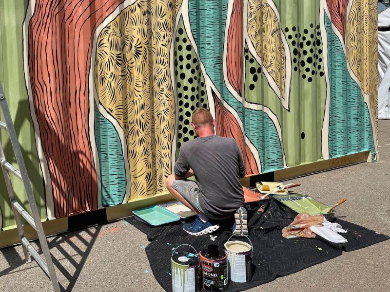 Artist Paints a Mural on a storage container during the Ann Arbor Art Fair