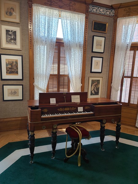 A pianoforte with artwork in the background
